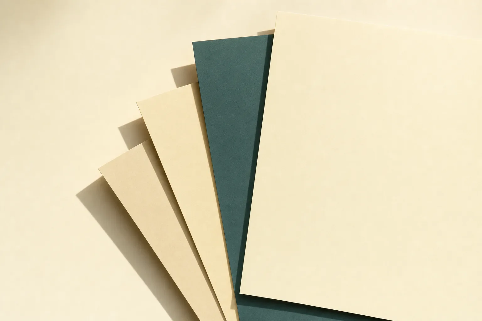 Layered sheets of cream and white paper on a warm surface, edges overlapping in soft daylight.
